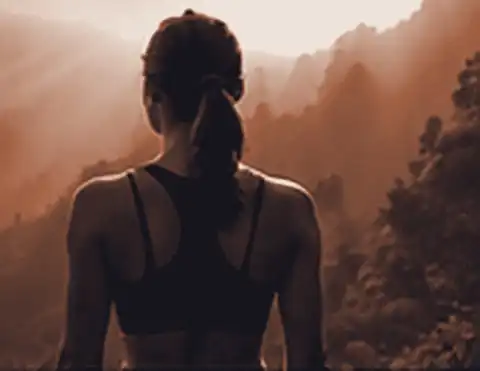 Woman looking out over misty mountains at sunrise